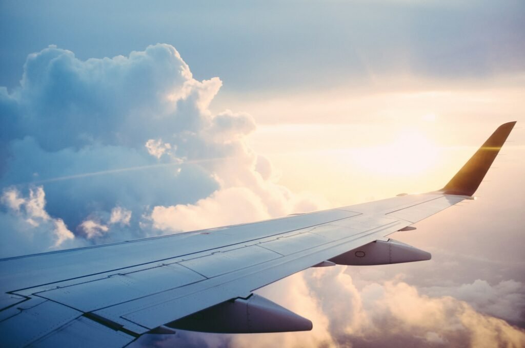 Aircraft wing above the clouds at sunset, representing international travel