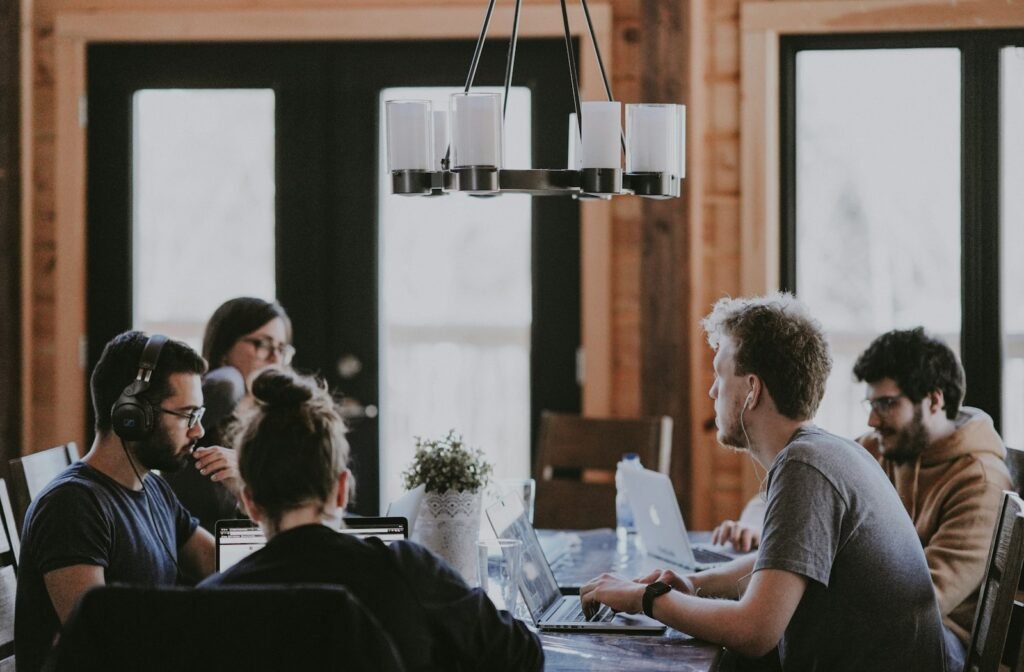 A small team working together at a long table with laptops